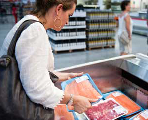 Frau schaut verpackten Fisch im Supermarkt an