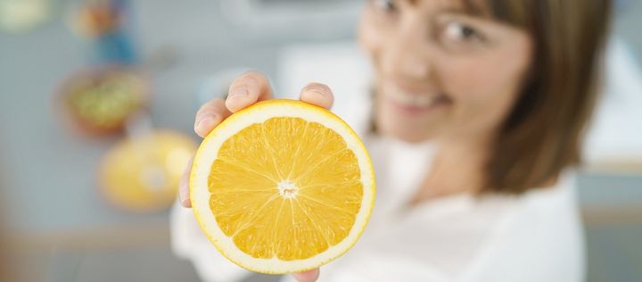 Frau hält Hälfte einer Orange hoch
