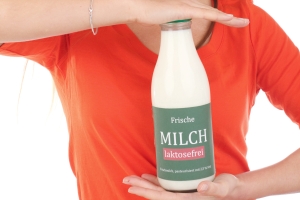 Frau hält Flasche laktosefreie Milch zwischen den Händen