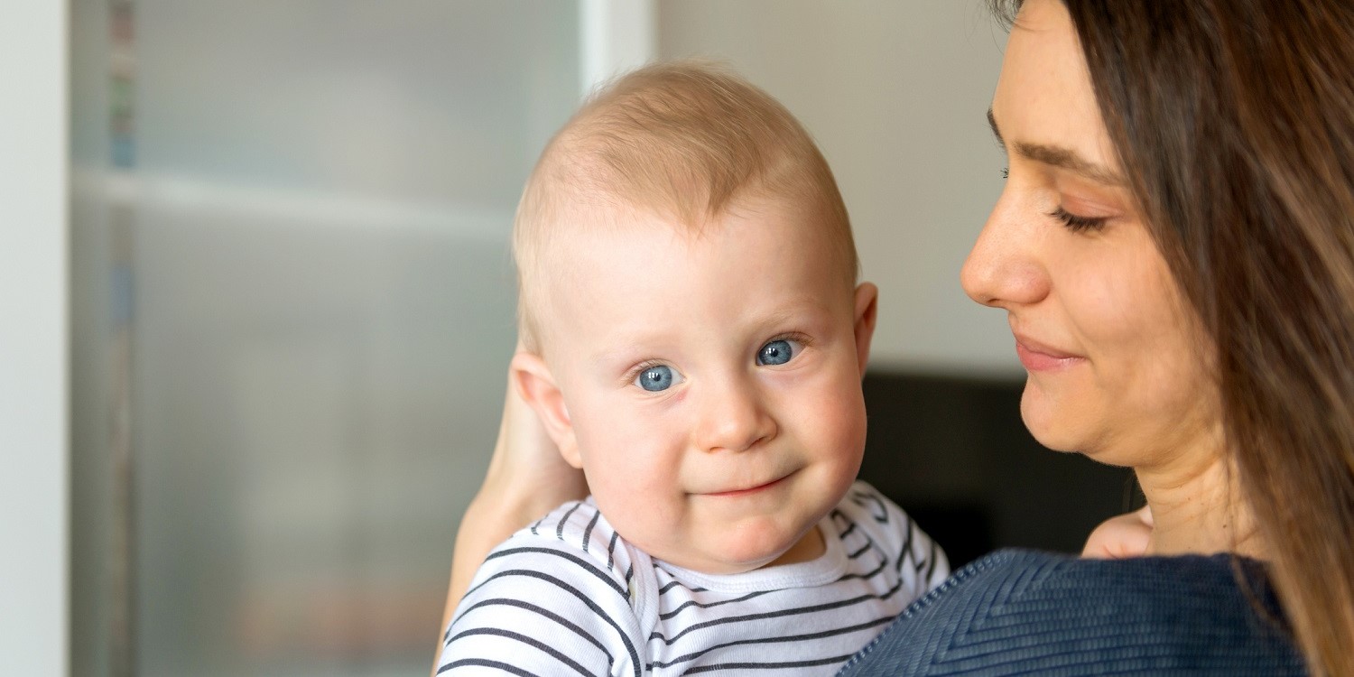 Eine Mutter hält ihr Baby von etwa sechs Monaten auf dem Arm. . Artikel "Stillzeit ohne Stress beenden" öffnen.