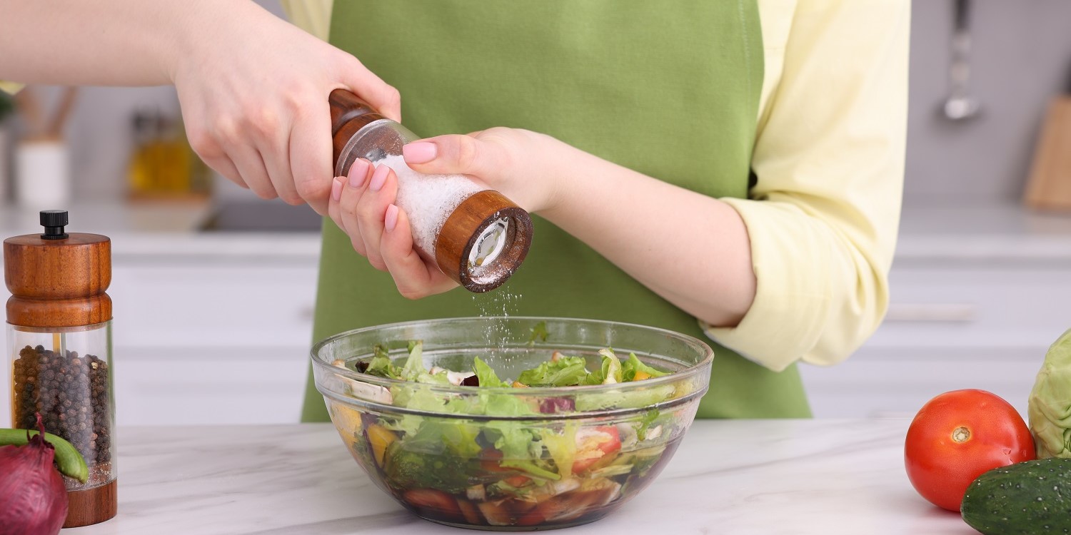 Eine Frau gibt mit einer Salzmühle Salz an eine Schüssel mit Salat. . Artikel "Neue Empfehlungen für die Jodzufuhr" öffnen.